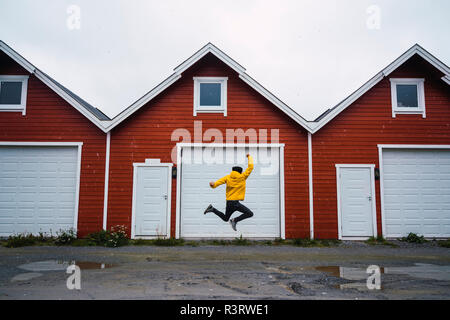 Norway, man jumping in front of row of huts Stock Photo