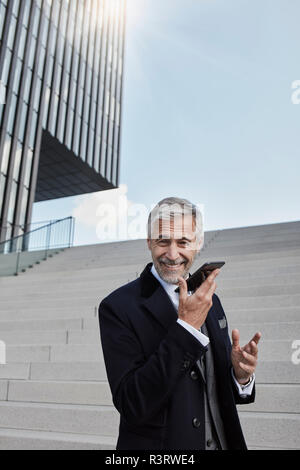 Portrait of content businessman on the phone standing in front of stairs Stock Photo