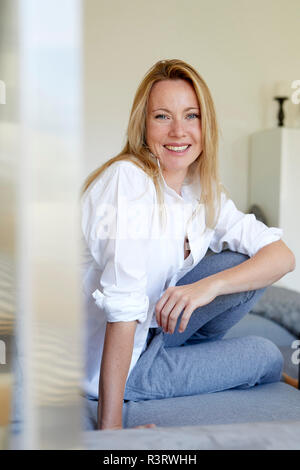 Happy woman sitting on couch, laughing Stock Photo