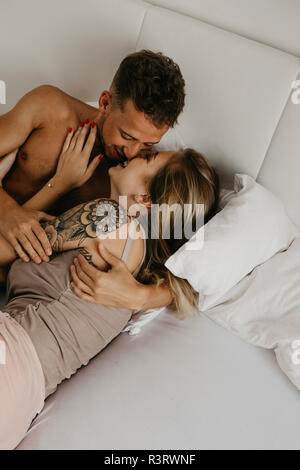 Happy young couple kissing in bed Stock Photo