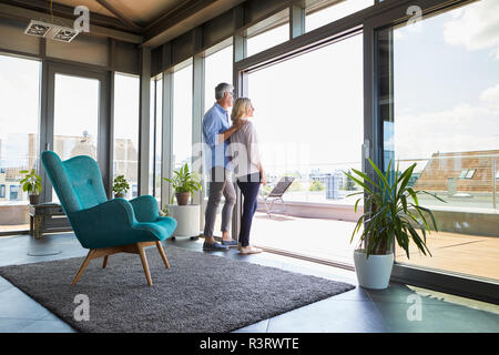 Mature couple looking out of window at home Stock Photo