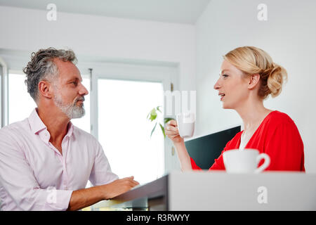 Two colleagues with coffee cups talking in office Stock Photo