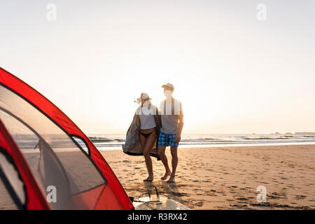 Romantic couple camping on the beach, doing a beach stroll at sunset Stock Photo