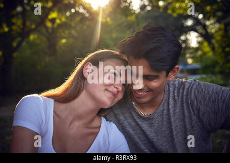Romantic young couple sitting in park, enjoying sunset Stock Photo