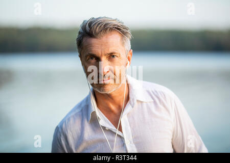 Portrait of man listening music with earphones at lake Stock Photo