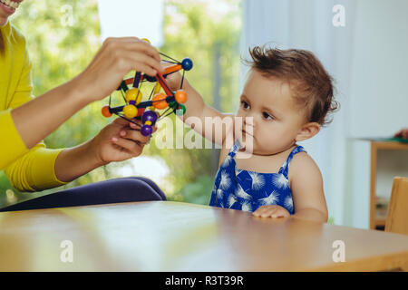 Mother and baby daughter playing at table at home Stock Photo