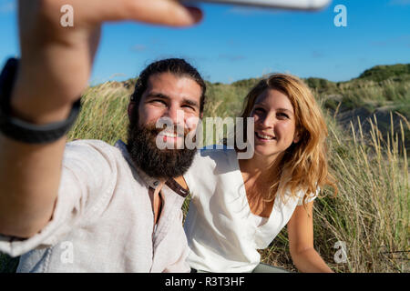 Happy couple taking smartphone selfie in nature Stock Photo