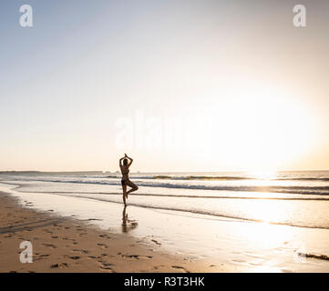 Young woman practicing yoga on the beach Stock Photo