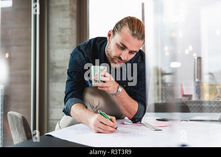 Young businessman working on plan at desk in office Stock Photo