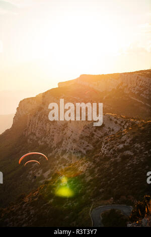 Spain, Silhouette of paraglider soaring high above the mountains at sunset Stock Photo