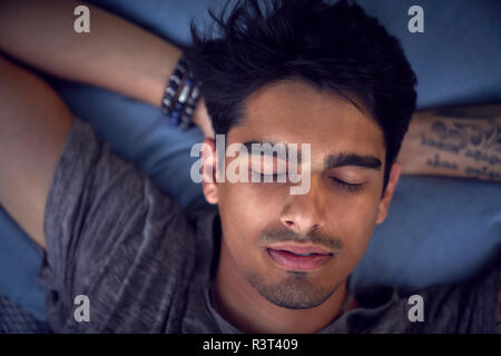 Young man with tattoo, relaxing on cushion Stock Photo