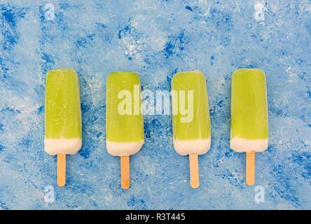 Row of four lime mint popsicles on light blue background Stock Photo