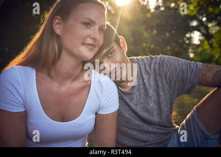 Romantic young couple sitting in park, enjoying sunset Stock Photo