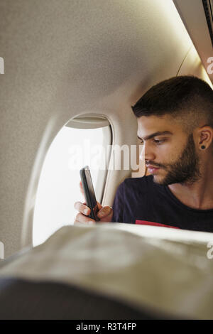 Young man in a plane with cell phone Stock Photo
