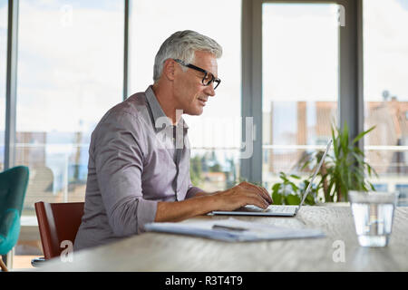 Mature man using laptop on table at home Stock Photo
