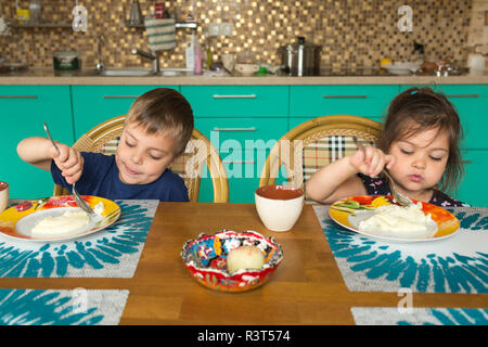 Portrait of boy and his little sister eating breakfast in the kitchen Stock Photo