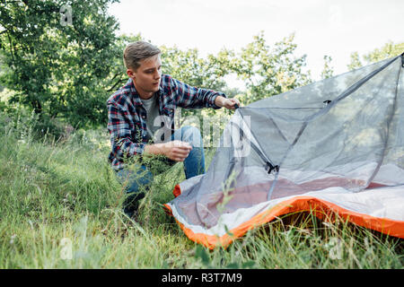 Young man camping in nature, setting up tent Stock Photo