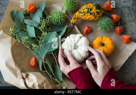 Autumnal decoration, woman's hand taking ornamental pumpkin Stock Photo