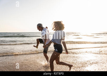 Young couple having fun at the beach, splashing water in the sea Stock Photo