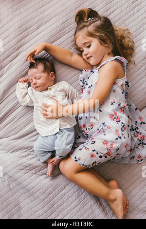 Girl lying on blanket cuddling with her baby brother