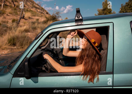 Smiling young woman wearing a hat sitting in a car Stock Photo