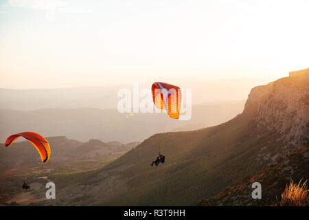 Spain, Silhouette of paraglider soaring high above the mountains at sunset Stock Photo