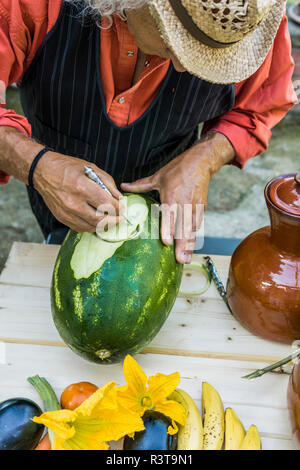 Senior man working on a watermelon with carving tool Stock Photo