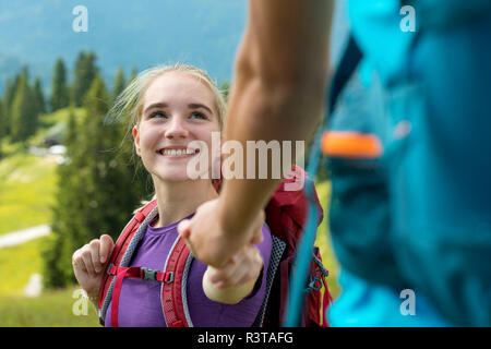 Germany, Bavaria, Brauneck near Lenggries, happy young woman hiking in alpine landscape holding hand of boyfriend