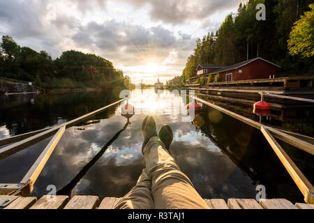 Finland, Kajaani, Man sitting on jetty, watching sunset Stock Photo