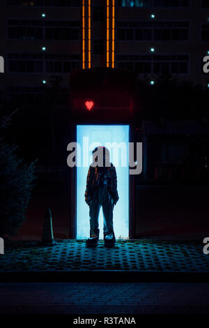 Spaceman standing at an illuminated box at night Stock Photo