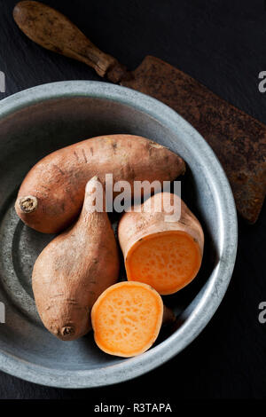 Sliced and whole sweet potato in metal bowl Stock Photo
