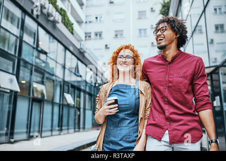 Colleagues walking together in the city, woman drinking coffee Stock Photo