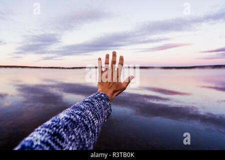 Hand of young man reaching out to the sky Stock Photo