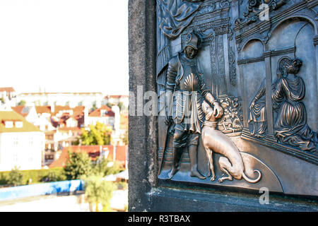 The plaque on the statue of John of Nepomuk with the dog, touching which means good luck. Charles bridge of Prague, Czech Republic Stock Photo