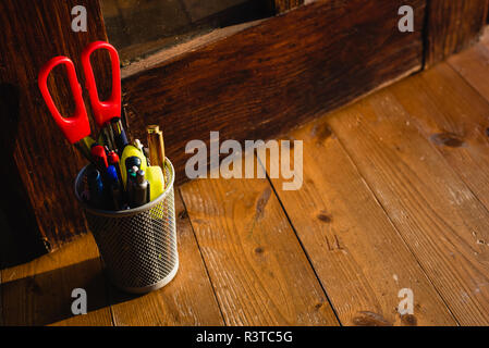 Pencil box full of pencil and scissors on the wooden floor. Stock Photo