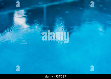 Drops of rain falling on the water of a pool. Stock Photo