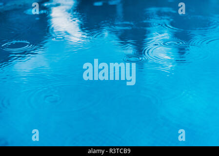 Drops of rain falling on the water of a pool. Stock Photo