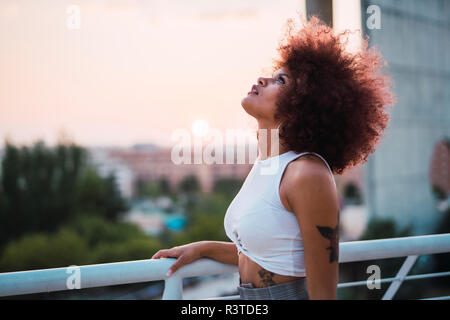 Portrait of young woman on terrace at evening twilight looking up Stock Photo