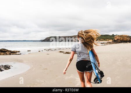 Young woman with surfboard running on the beach Stock Photo