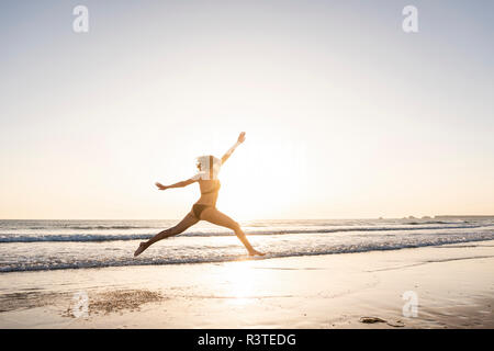 Young woman jumping for joy on the beach Stock Photo