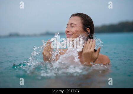 Young woman bathing in lake splashing with water Stock Photo