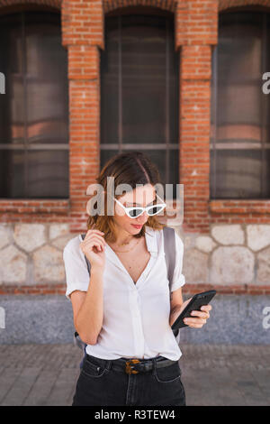 Young woman sight seeing in Madrid, using smartphone Stock Photo