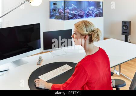 Young woman working on computer at desk in office Stock Photo