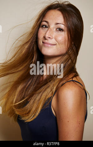 Portrait of freckled young woman with blowing hair Stock Photo