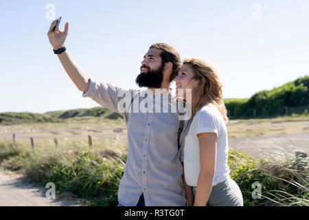 Young couple taking smartphone selfies on the beach Stock Photo