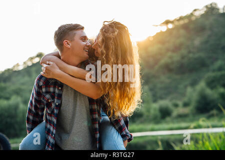 Romantic couple spending time in nature, kissing at sunset Stock Photo