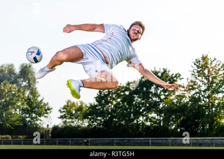 Young man kicking soccer ball Stock Photo