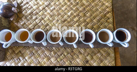 Row of testing white coffee cups on a weaved matt over a table. Stock Photo