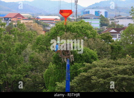worker sit on concrete mixer and crane hook lifting container in construction site Stock Photo