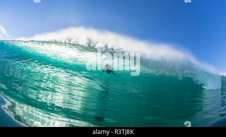 Surfer surfing action motion to escape ocean wave with push underwater through  a closeup water photo of encounter. Stock Photo